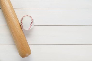 Beyzbol sopası ve top beyaz ahşap masada, üst manzarada yazı için yer var. Spor malzemeleri.