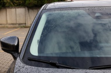 Araba silecekleri ön camdan su damlatıyor, yakın plan.