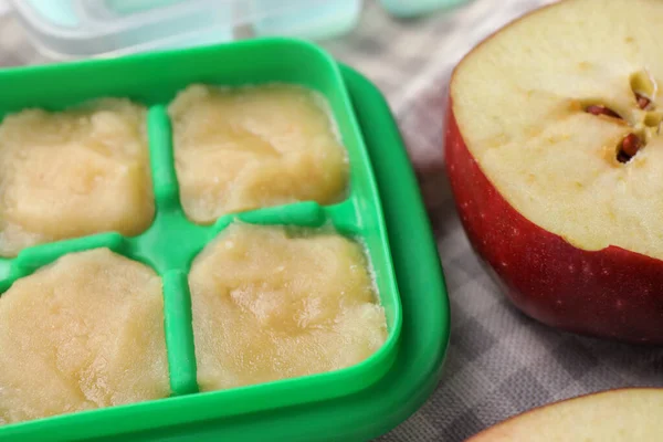 Apple puree in ice cube tray with ingredients on table, closeup