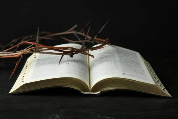 Bible and crown of thorns on black table