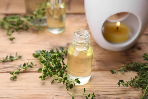 Thyme essential oil and fresh plant on wooden table, space for text