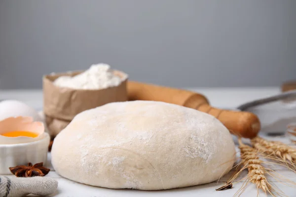 Fresh dough and ingredients on white wooden table, closeup