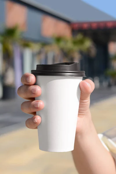 Woman holding takeaway coffee cup outdoors, closeup