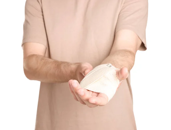 Man with hand wrapped in medical bandage on white background, closeup