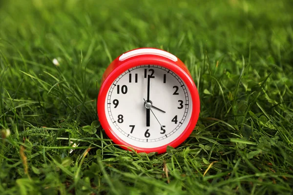 屋外の緑の芝生の上の赤い目覚まし時計 — ストック写真