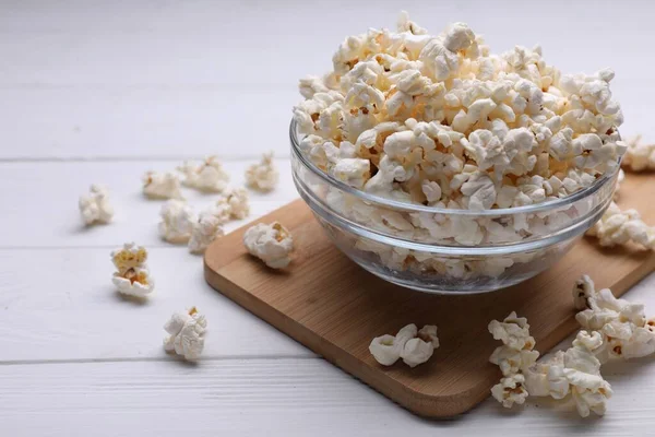 Tasty popcorn in bowl on white wooden table