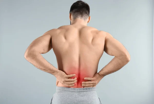 Young Man Suffering Back Pain Light Background — Stock Photo, Image