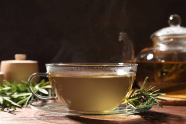 Bir fincan aromatik bitki çayı ve ahşap masada taze biberiye.