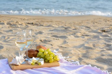 Beyaz şaraplı bardaklar ve kumlu sahilde atıştırmalıklar. Metin için boşluk