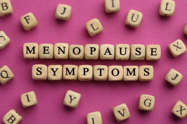 Wooden cubes with words Menopause Symptoms on pink background, flat lay clipart