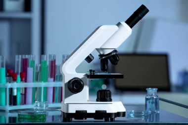 Modern mikroskop laboratuardaki metal masa üzerinde, mavi tonda.