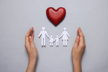 Gri arka planda gazete aile resimlerini koruyan bir kadın. Sigorta konsepti