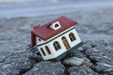 Çatlak asfaltta ev modeli. Deprem felaketi