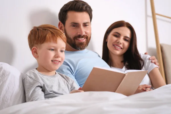 Šťastní Rodiče Svým Dítětem Čtení Knihy Posteli Doma — Stock fotografie