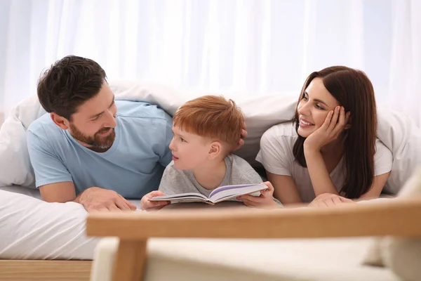Pais Felizes Com Seu Filho Lendo Livro Cama Casa — Fotografia de Stock