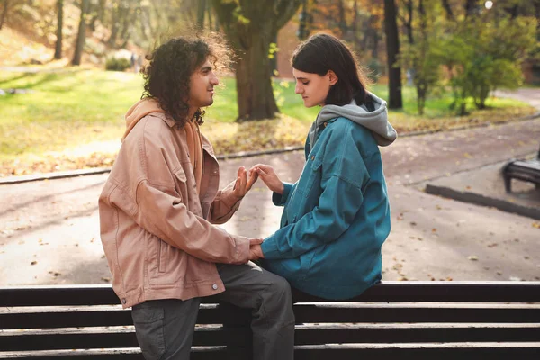 stock image Young couple spending time together on wooden bench in autumn park, space for text. Dating agency