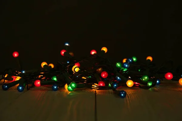 Hermosas Luces Brillantes Navidad Mesa Madera Sobre Fondo Negro —  Fotos de Stock