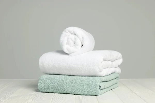Zachte Handdoeken Witte Houten Tafel Tegen Lichtgrijze Achtergrond — Stockfoto
