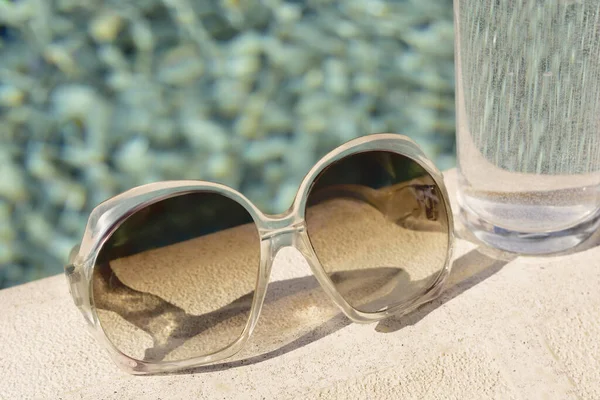 Elegantes Gafas Sol Vaso Agua Cerca Piscina Aire Libre Día —  Fotos de Stock