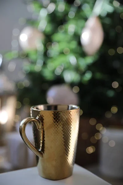 Golden cup of hot drink indoors. Christmas time