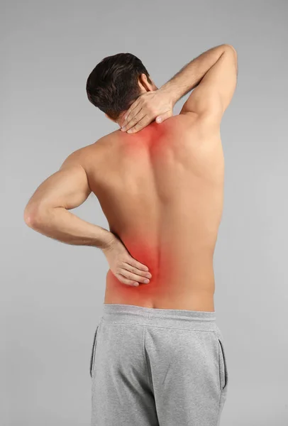 Young Man Suffering Back Pain Grey Background — Stock Photo, Image