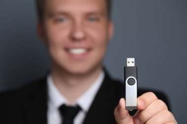 USB bellekli adam gri arka plana karşı, cihaza odaklan. Metin için boşluk