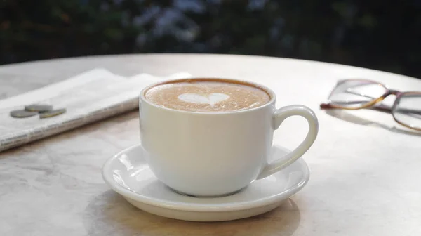 外のベージュ大理石のテーブルの上においしいコーヒー グラス 新聞のカップ — ストック写真