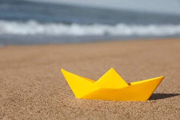 stock image Yellow paper boat near sea on sandy beach, space for text