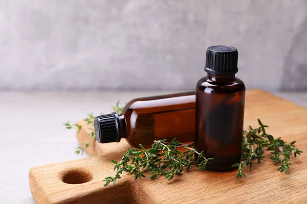 Wooden board with thyme essential oil on table, closeup