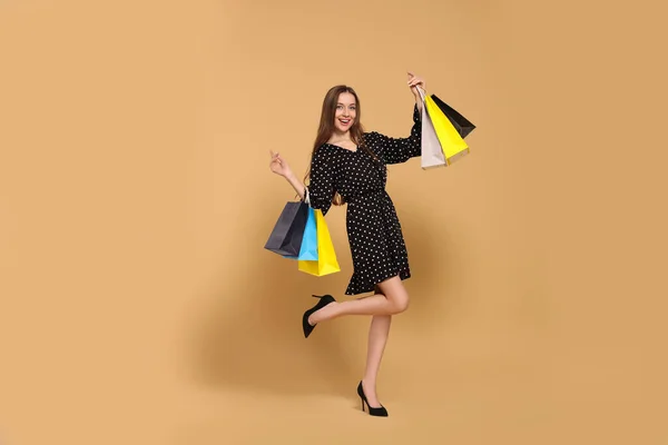 Stylische Junge Frau Mit Einkaufstaschen Auf Beigem Hintergrund — Stockfoto