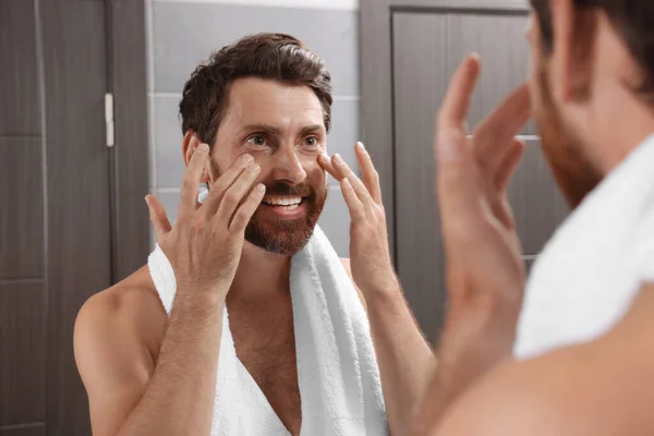 木製のドアの近くのバスルームで鏡を見てハンサムな髭の男 — ストック写真