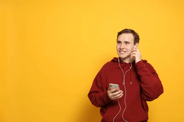 Przystojny Młodzieniec Słuchawkami Smartfonem Żółtym Tle Miejsce Tekst — Zdjęcie stockowe
