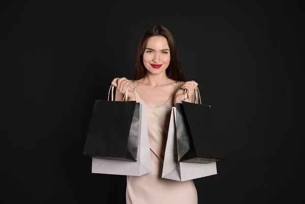 快乐的年轻女人 背着黑色背景的购物袋 大甩卖 — 图库照片