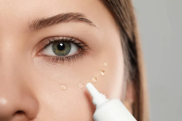 Young Woman Applying Cream Eye Light Grey Background Closeup — Stock Photo, Image