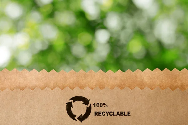 緑の背景がぼやけてリサイクルのシンボルを持つ紙袋 環境に優しいパッケージ — ストック写真