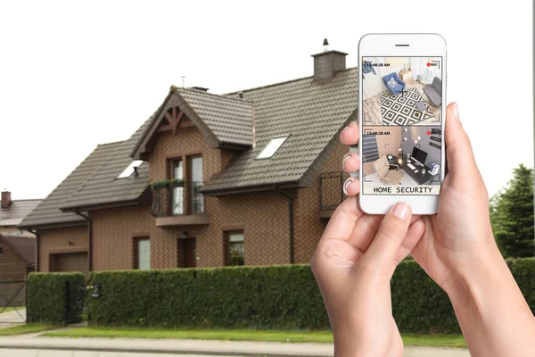 Home security system. Woman monitoring CCTV cameras on smartphone near her house, closeup