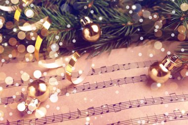 Firavun dalları ve altın toplar Noel notaları üzerinde, manzaranın üstünde. Bokeh etkisi