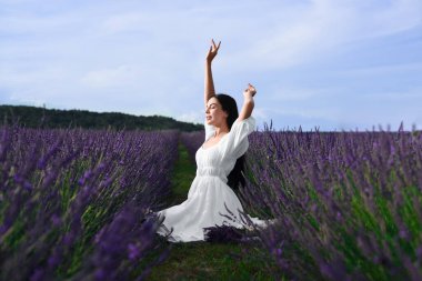 Beautiful young woman sitting in lavender field