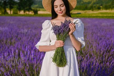 Beautiful young woman with bouquet in lavender field