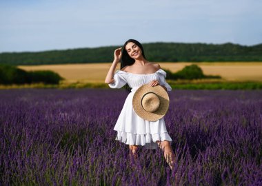 Beautiful young woman walking in lavender field