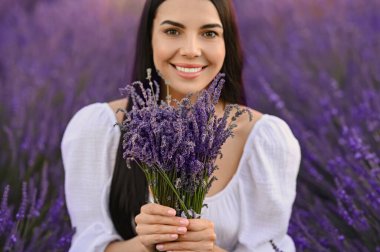 Beautiful young woman with bouquet in lavender field