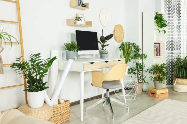 Comfortable workplace with modern computer and different houseplants in room