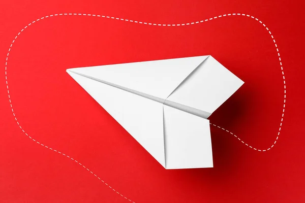 Handmade white paper plane on red background, top view