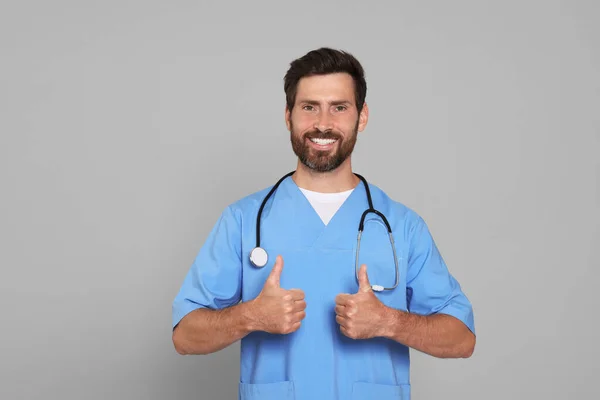 Arzt Mit Stethoskop Zeigt Daumen Nach Oben Auf Hellgrauem Hintergrund — Stockfoto
