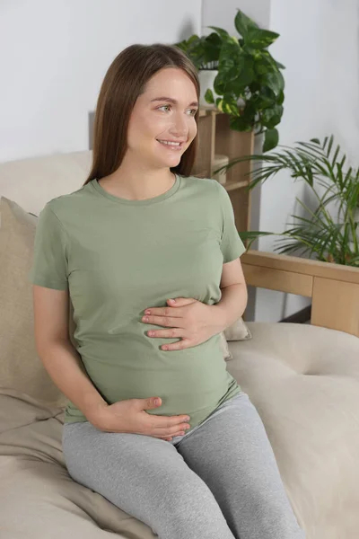 Feliz Mujer Embarazada Sentada Sofá Tocando Vientre Sala Estar — Foto de Stock