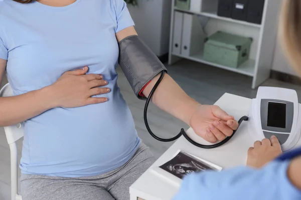 stock image Doctor measuring blood pressure of pregnant woman in hospital, closeup