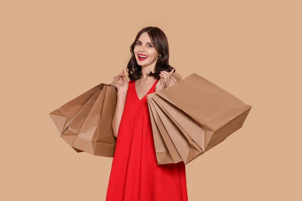 Schöne Junge Frau Mit Papiereinkaufstaschen Auf Beigem Hintergrund — Stockfoto
