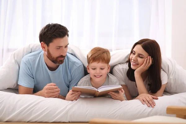 Lyckliga Föräldrar Med Sitt Barn Läser Bok Sängen Hemma — Stockfoto