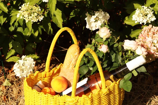 Gelber Weidensack Mit Rosen Pfirsichen Baguette Und Wein Auf Grünem — Stockfoto