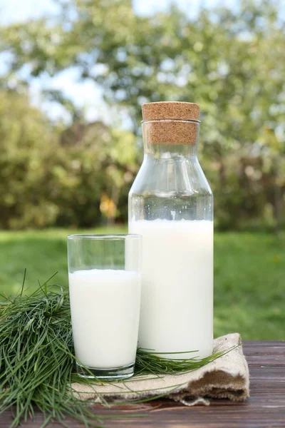 木のテーブルの上においしい新鮮な牛乳と緑の草 — ストック写真